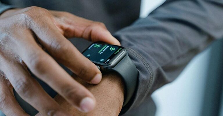 Close-up of a hand tapping a smartwatch showing a workout tracking screen, representing sports technology and wearables.