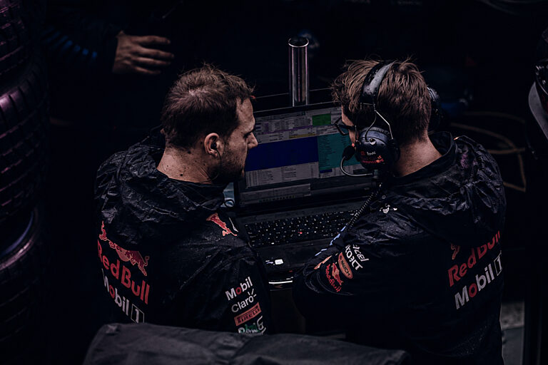 Zwei Personen mit Headsets vor Monitoren in einem Kontrollraum
